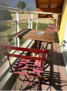 uma mesa de madeira e 2 cadeiras numa varanda em Location Chambres Le Panorama - Aéroport Genève - Pays de Gex em Chevry