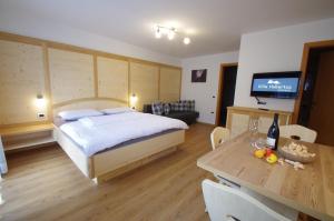 a bedroom with a bed and a table with a television at Villa Hubertus in Ortisei