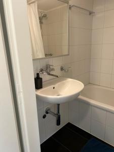 La salle de bains blanche est pourvue d'un lavabo et d'une baignoire. dans l'établissement Guesthouse Elisa 6, à Zurich