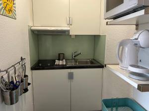 una pequeña cocina con fregadero y microondas en Guesthouse Elisa 6 en Zúrich