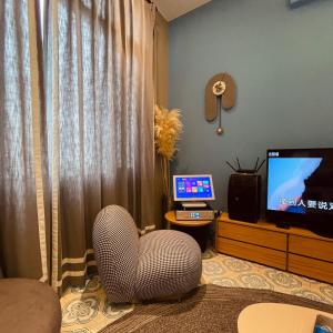 a living room with a chair and a television at Akasaka Family Villa in Anping