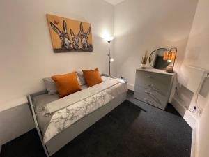 1 dormitorio con 1 cama con almohadas de color naranja en Urban 3 Bedroom Home in Kings Heath-Great Location, en Birmingham