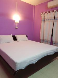 Cama grande en habitación con pared morada en Baan Nakarin Guest House บ้านนครินทร์ en Patong