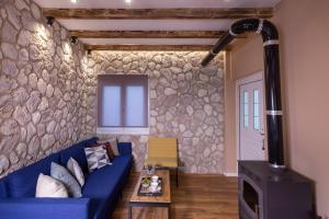 sala de estar con sofá azul y pared de piedra en Tzoumerka Secret House, en Vourgareli