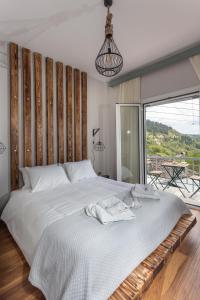 1 dormitorio con 1 cama blanca grande y balcón en Tzoumerka Secret House, en Vourgareli