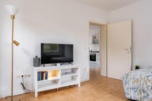 een woonkamer met een tv op een witte kast bij West48 Gemütliches Apartment -Blick auf Blauen See in Duisburg
