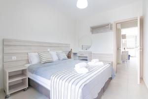 a white bedroom with a large bed and a mirror at Neos Marmaras Family Suite in Neos Marmaras