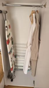 a closet with white clothes hanging on a rod at Уютные апартаменты in Almaty