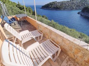 - un ensemble de chaises assises sur une terrasse couverte donnant sur l'eau dans l'établissement Peaceful Holiday House Senija, à Vela Luka