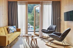 ein Wohnzimmer mit einem Sofa und 2 Stühlen in der Unterkunft Natürlich Hell. Aparthotel & Camping in Fügen