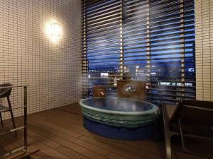uma grande banheira num quarto com uma grande janela em The BREAKFAST HOTEL Fukuoka Nakasu em Fukuoka