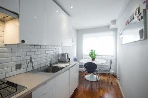 een witte keuken met een wastafel en een tafel bij Platform 9 3/4 by condokeeper in Londen