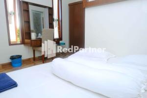 a bedroom with a white bed and a mirror at Guest House Bibong Makassar Mitra RedDoorz in Makassar