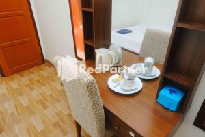 a room with a table and chairs and a bed at Guest House Bibong Makassar Mitra RedDoorz in Makassar