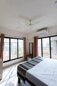 a bedroom with a bed and large windows at Lotus 3BHK by SoulStays in Dapoli