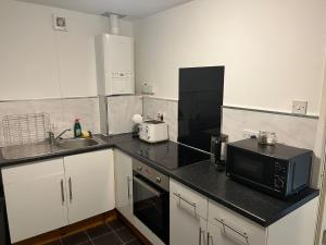 cocina con encimera negra y microondas en Topzy-Turvy - 1 Bedroom Apartment en Swansea