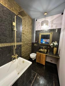a bathroom with a tub and a toilet and a sink at DarkHouse Versace Blue in Łódź