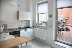 uma cozinha com armários brancos, uma mesa e uma janela em Appartements am Markt em Greifswald