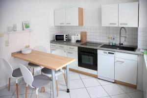 a kitchen with a wooden table and white cabinets at Appartements am Markt in Greifswald
