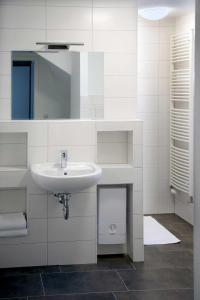 a white bathroom with a sink and a mirror at Appartements am Markt in Greifswald