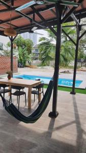 a hammock on a patio with a table and a pool at Sayang Di Kaki Bukit Homestay Near Icon City Bukit Mertajam in Bukit Mertajam