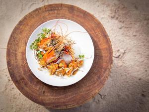 un plato blanco de comida en un plato de madera en Coral Rocks Hotel & Restaurant, en Jambiani