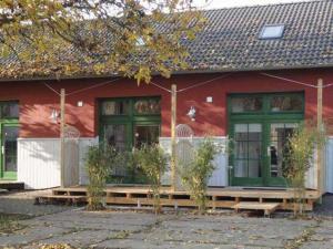 Casa roja con puertas verdes y porche en Ferienwohnungen am Museumshafen en Greifswald