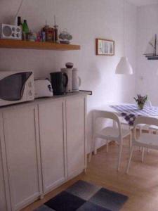 a kitchen with a table with a microwave and a table with chairs at Ferienwohnungen am Museumshafen in Greifswald