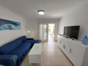 uma sala de estar com um sofá azul e uma televisão de ecrã plano em Apartamentos Acali em San Agustín