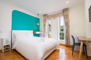 sypialnia z dużym białym łóżkiem i biurkiem w obiekcie Sunset Bãi Dâu Boutique Hotel Vũng Tàu w mieście Vung Tau