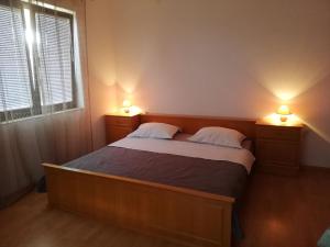 a bedroom with a bed with two lamps on it at Apartmani Danica in Pirovac