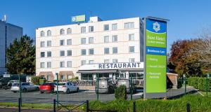 un bâtiment avec un panneau en face d'un parking dans l'établissement Sure Hotel by Best Western Bordeaux Lac, à Bordeaux