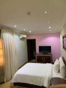 Schlafzimmer mit einem weißen Bett und einem Flachbild-TV in der Unterkunft Conference Hotel & Suites Ijebu in Ijebu Ode