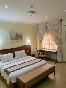 a bedroom with a bed and a desk and a window at Conference Hotel & Suites Ijebu in Ijebu Ode