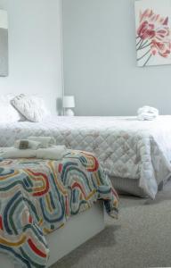 um quarto com uma cama branca e um edredão colorido em Sylvan Beach Resort em Bellara