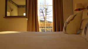 ein Schlafzimmer mit einem weißen Bett und einem Fenster in der Unterkunft Villa Bonomo Charme Hotel in Asiago