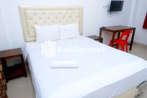 um quarto com uma cama branca e uma mesa em Fortuner Homestay Syariah Makassar Mitra RedDoorz em Pampang