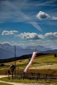 a flag on a fence in a field with mountains at Starkenfeldhütte in Rodengo