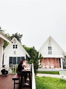 dos personas sentadas en una mesa frente a una casa en ภูฝ้ายวิลล่า Phufai villa en Chiang Khan