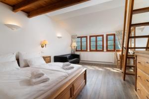 um quarto com uma grande cama branca e uma cadeira em Pension Slunečnice & Restaurace Farma em Spindleruv Mlyn