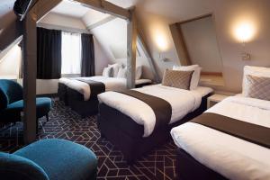 a hotel room with three beds and a chair at Hotel CC in Amsterdam