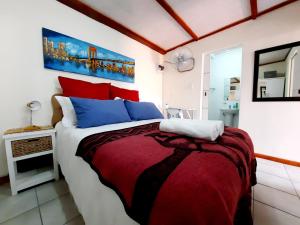 a bedroom with a bed with red and blue pillows at Cape Cozy Cottages in Cape Town