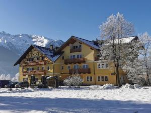 ein großes gelbes Gebäude mit Schnee auf dem Boden in der Unterkunft Hotel Gasthof Schweizerhaus in Stuhlfelden