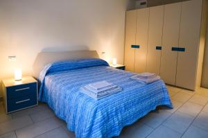 a bedroom with a bed with a blue blanket and cabinets at Appartamento Prada in Endine Gaiano