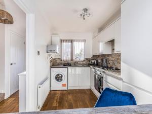 a kitchen with white cabinets and a blue chair at Pass the Keys Holiday Home Near Beaches in Chichester