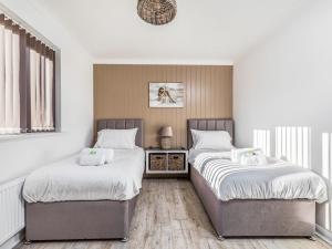 two beds in a bedroom with white walls and wood floors at Pass the Keys Holiday Home Near Beaches in Chichester