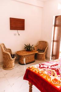 a room with wicker chairs and a table and a bed at Cocoon Auberge in Jaipur