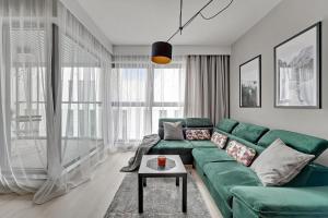 a living room with a green couch and a table at Flatbook - City Center Apartments Granaria I in Gdańsk