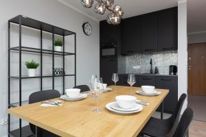 une salle à manger avec une table en bois et des armoires noires dans l'établissement Nowa Grochowska Apartments by Renters, à Varsovie