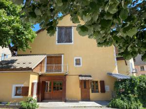 ein großes gelbes Haus mit Holztüren und einem Balkon in der Unterkunft Le Pied de Ville Pouzenc in Embrun
